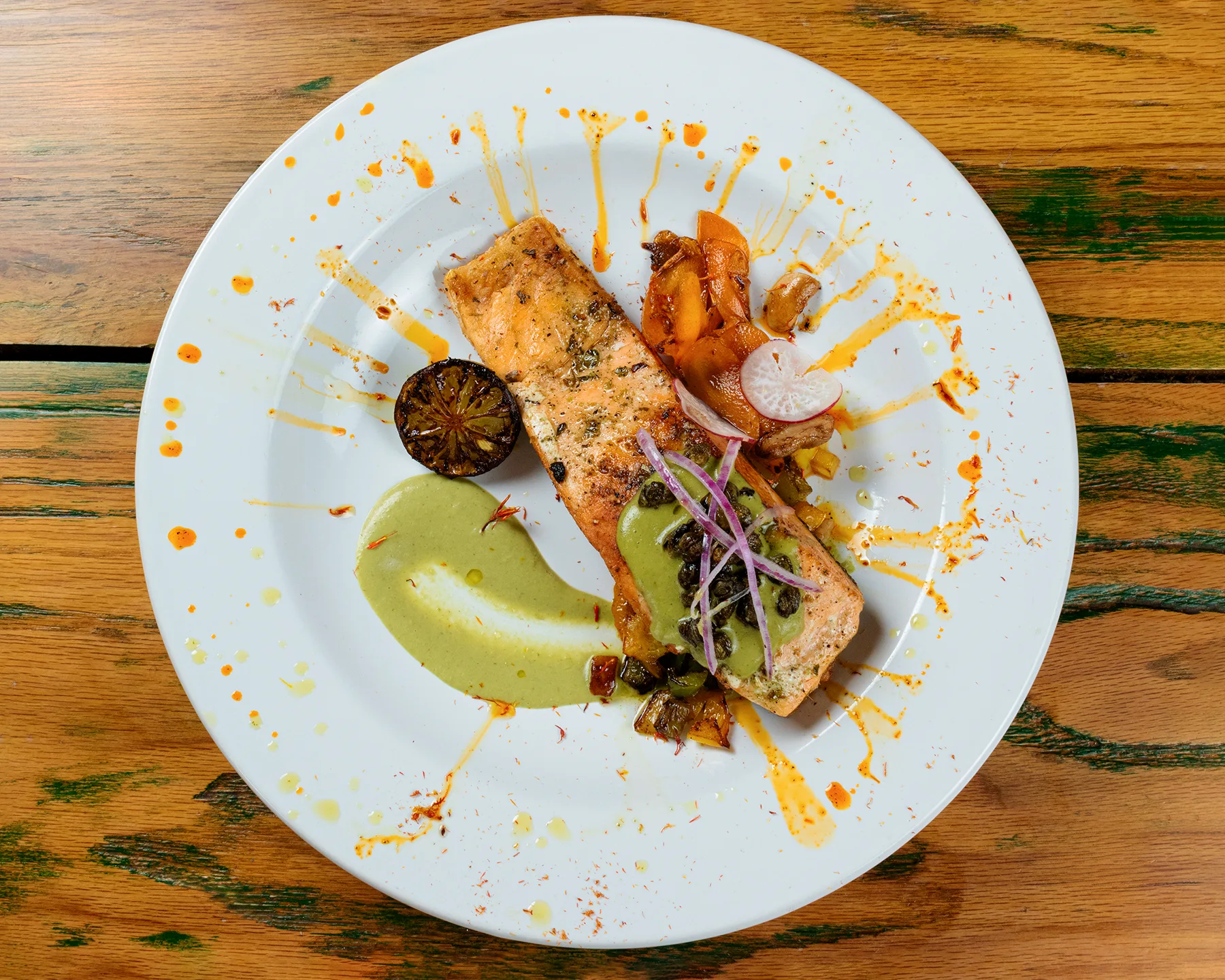 Plato gourmet de salmón al horno con salsa verde y vegetales frescos, fotografiado por un fotógrafo gastronómico en Chihuahua, México.