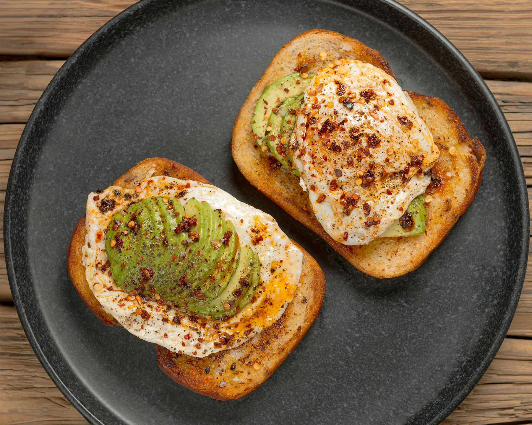 Deliciosas tostadas de aguacate con huevo frito y hojuelas de chile, capturadas en una fotografía gastronómica de alta calidad en Chihuahua.