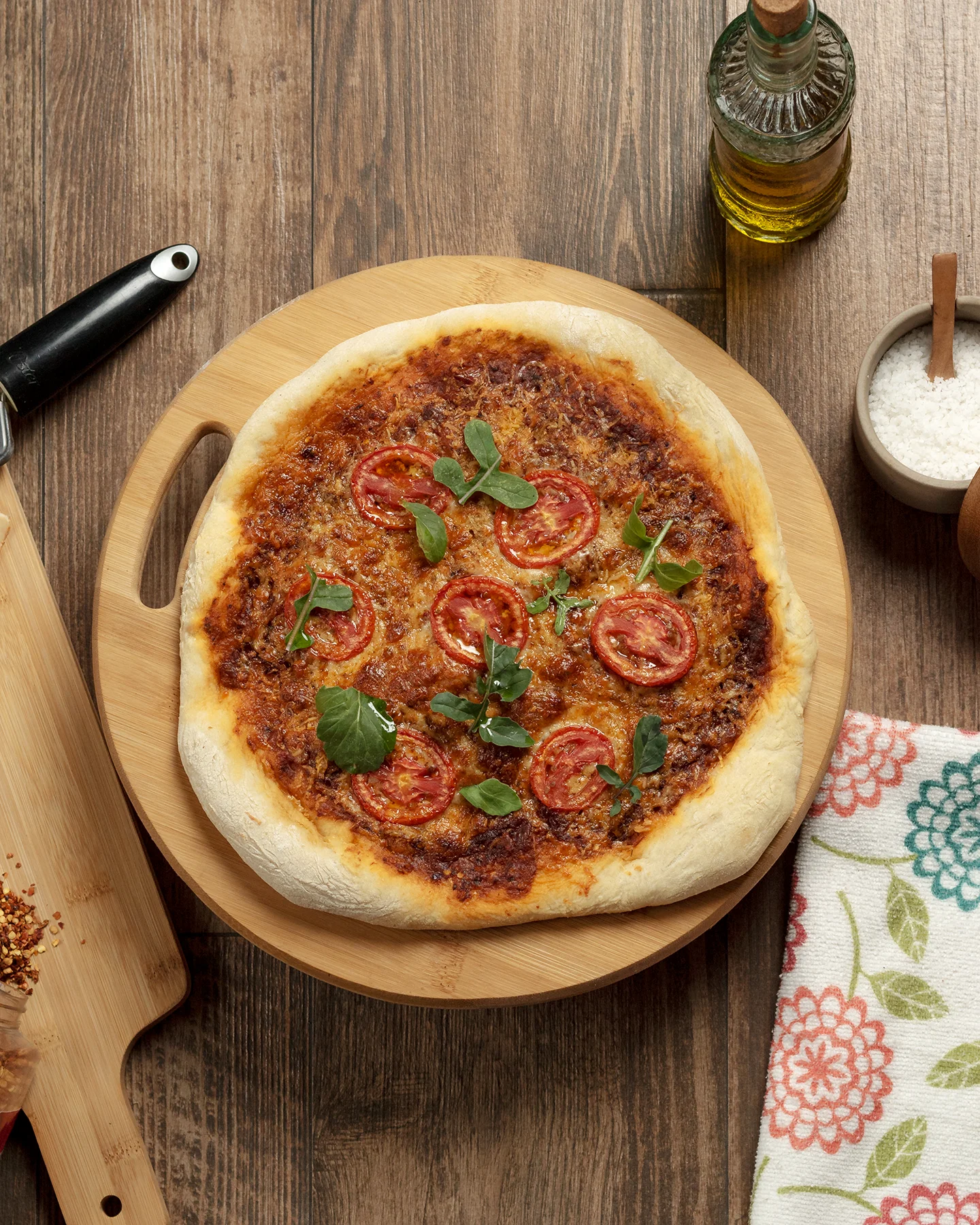 Pizza casera sobre tabla de madera, rodeada de ingredientes como sal gruesa, aceite de oliva y ají molido, en una composición cálida y rústica con luz natural.Fotografía cenital de una tostada con atún marinado en cubos y una espiral de aguacate en el centro, espolvoreada con semillas de sésamo y pimienta negra, sobre un plato oscuro.