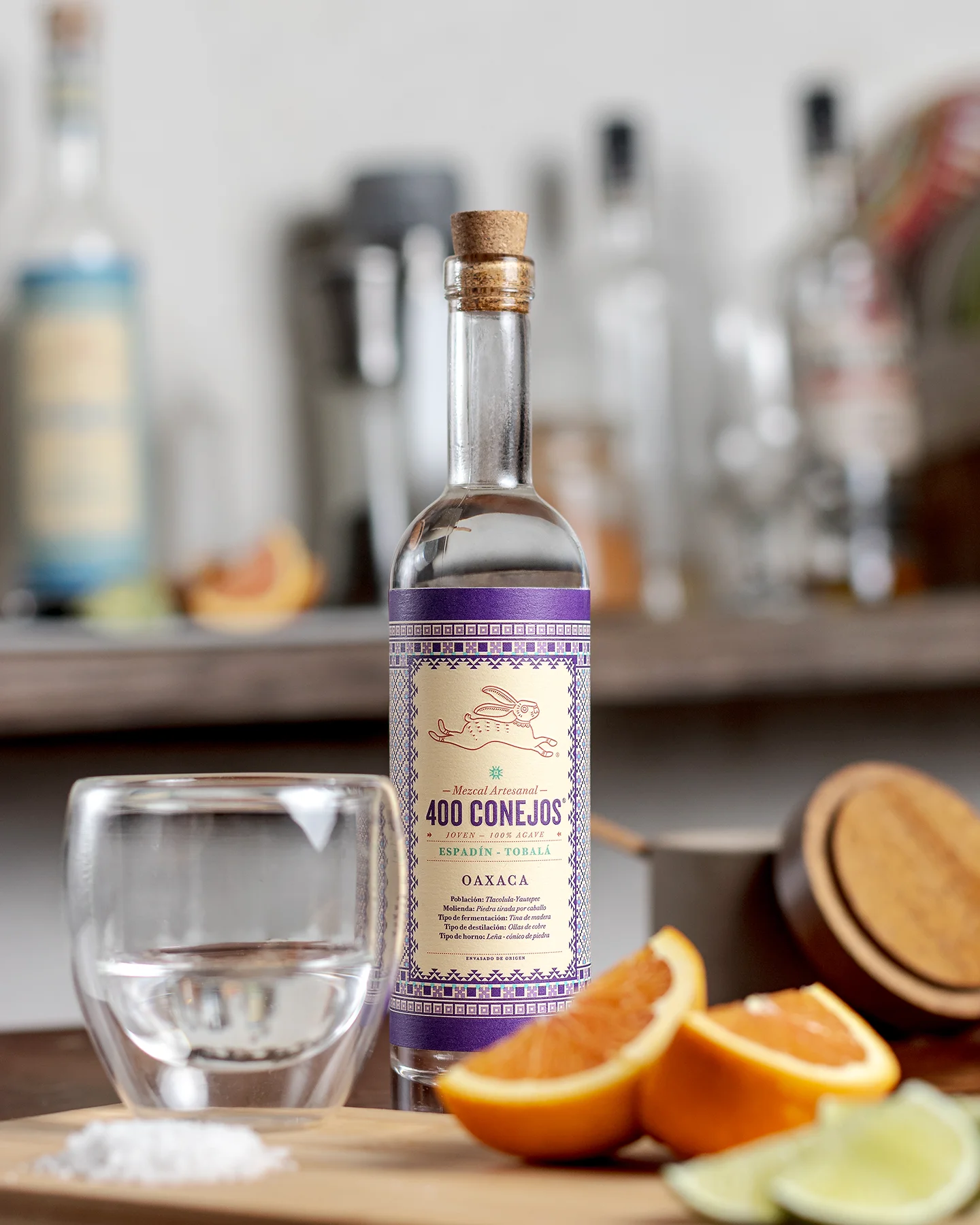 Fotografía de producto de una botella de mezcal ambientada con cosas con las que típicamente se toma.