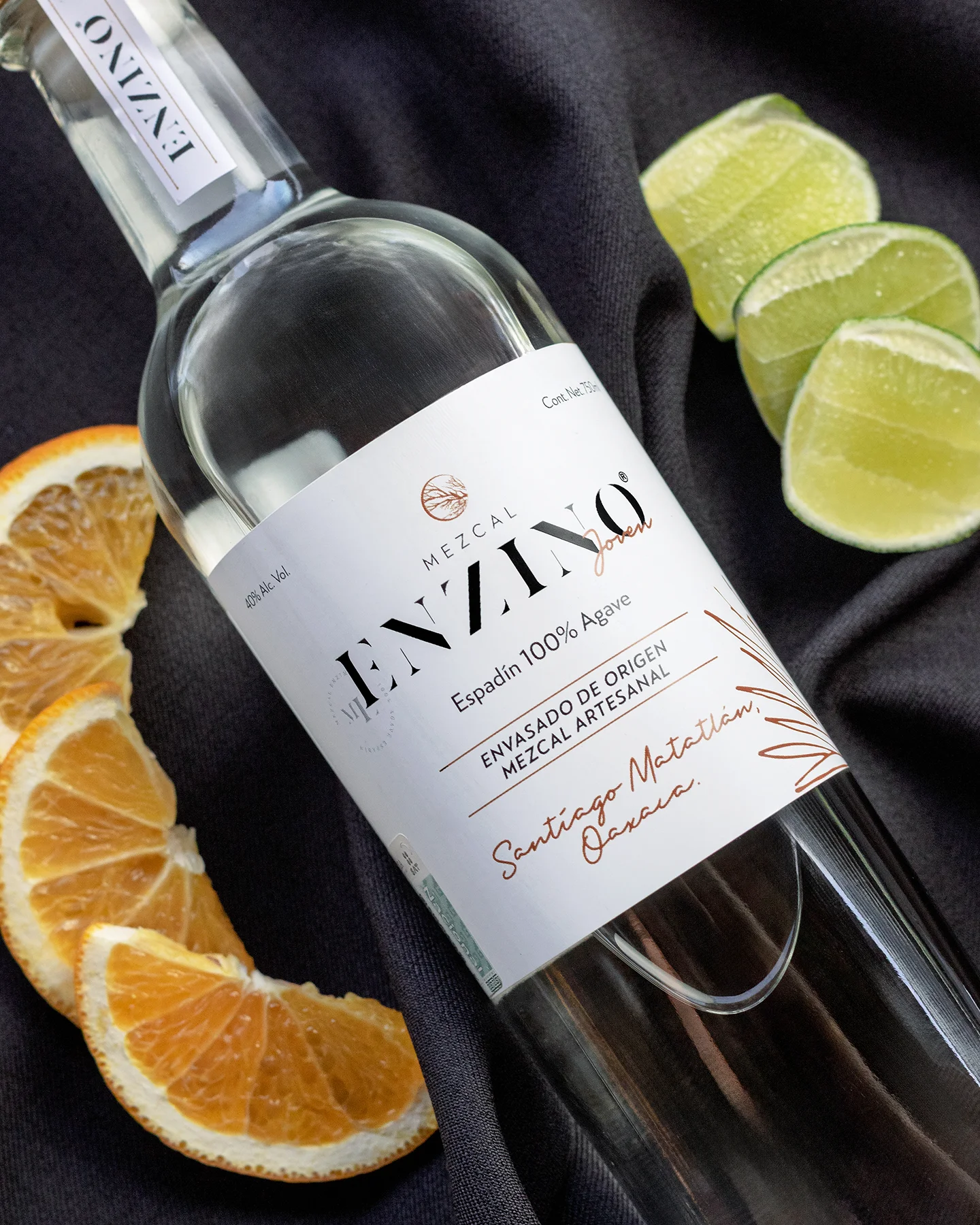 Botella de Mezcal acompañada de limon y naranja.