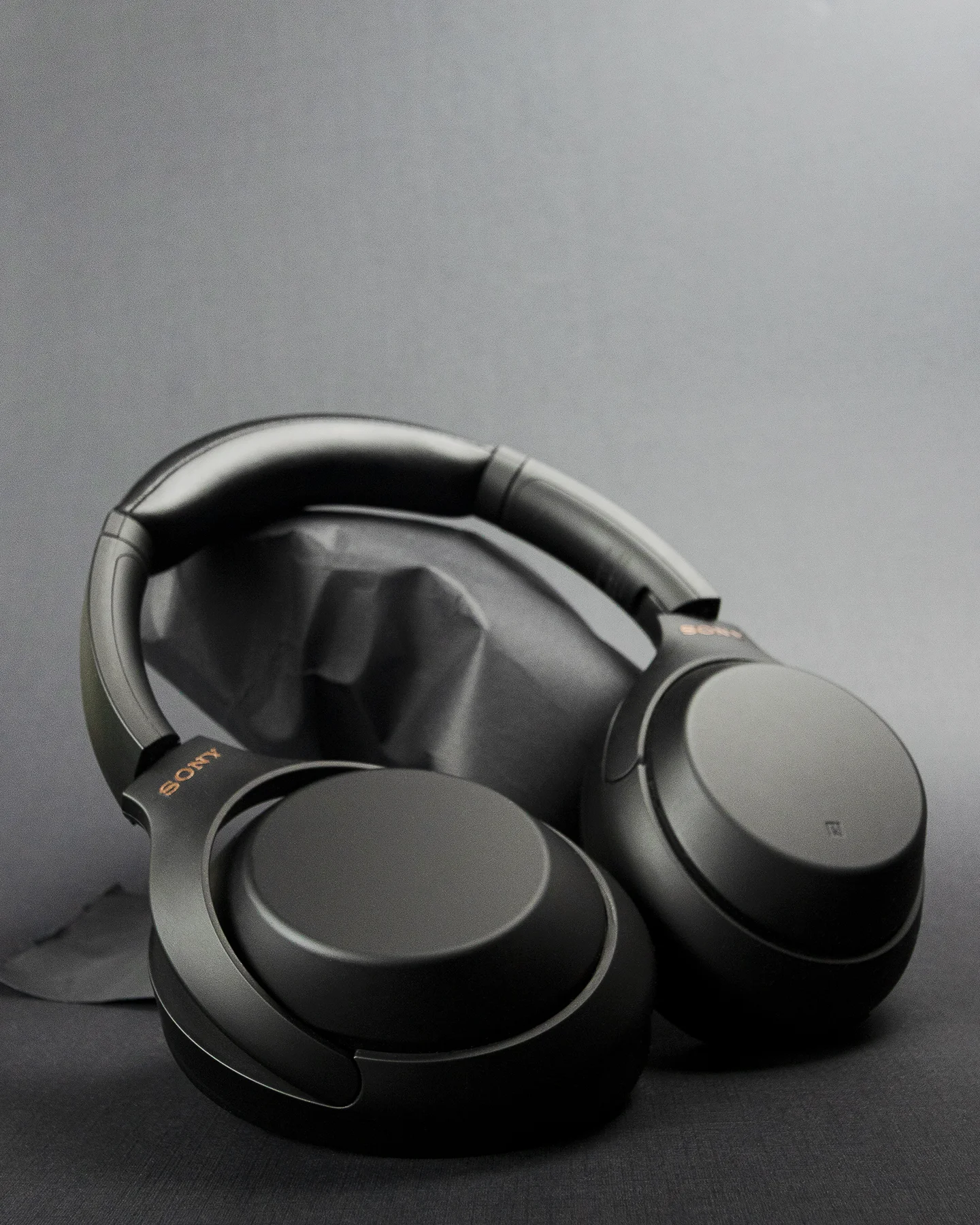 Audífonos negros sobre fondo gris oscuro con luz suave resaltando su diseño elegante..