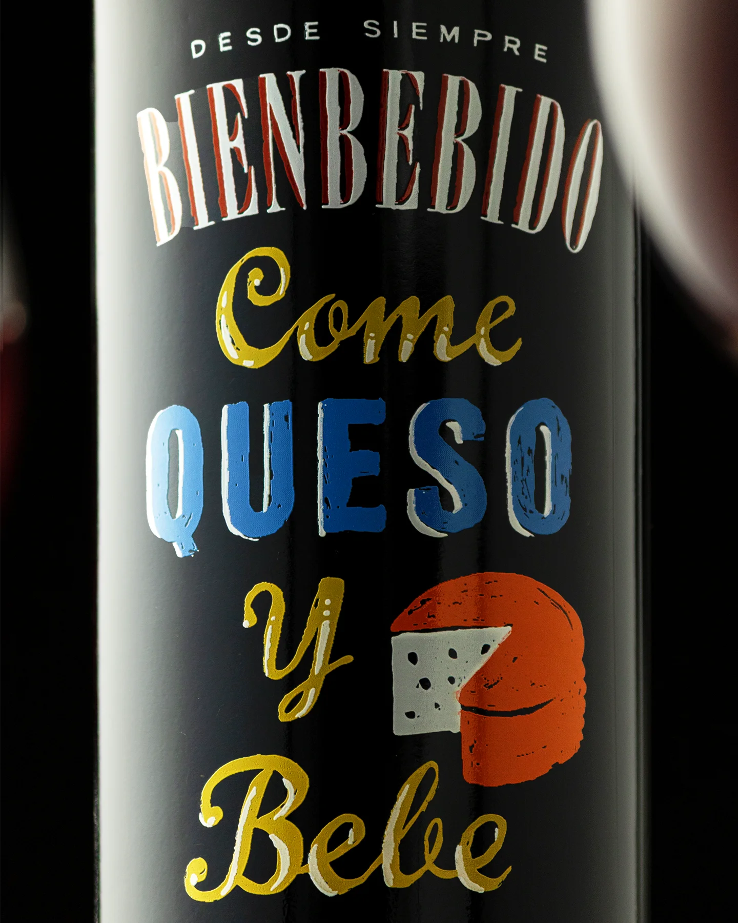 Detalle de etiqueta de botella de vino tinto con diseño tipográfico ilustrado, capturado en fotografía publicitaria con iluminación lateral para resaltar texturas y color.