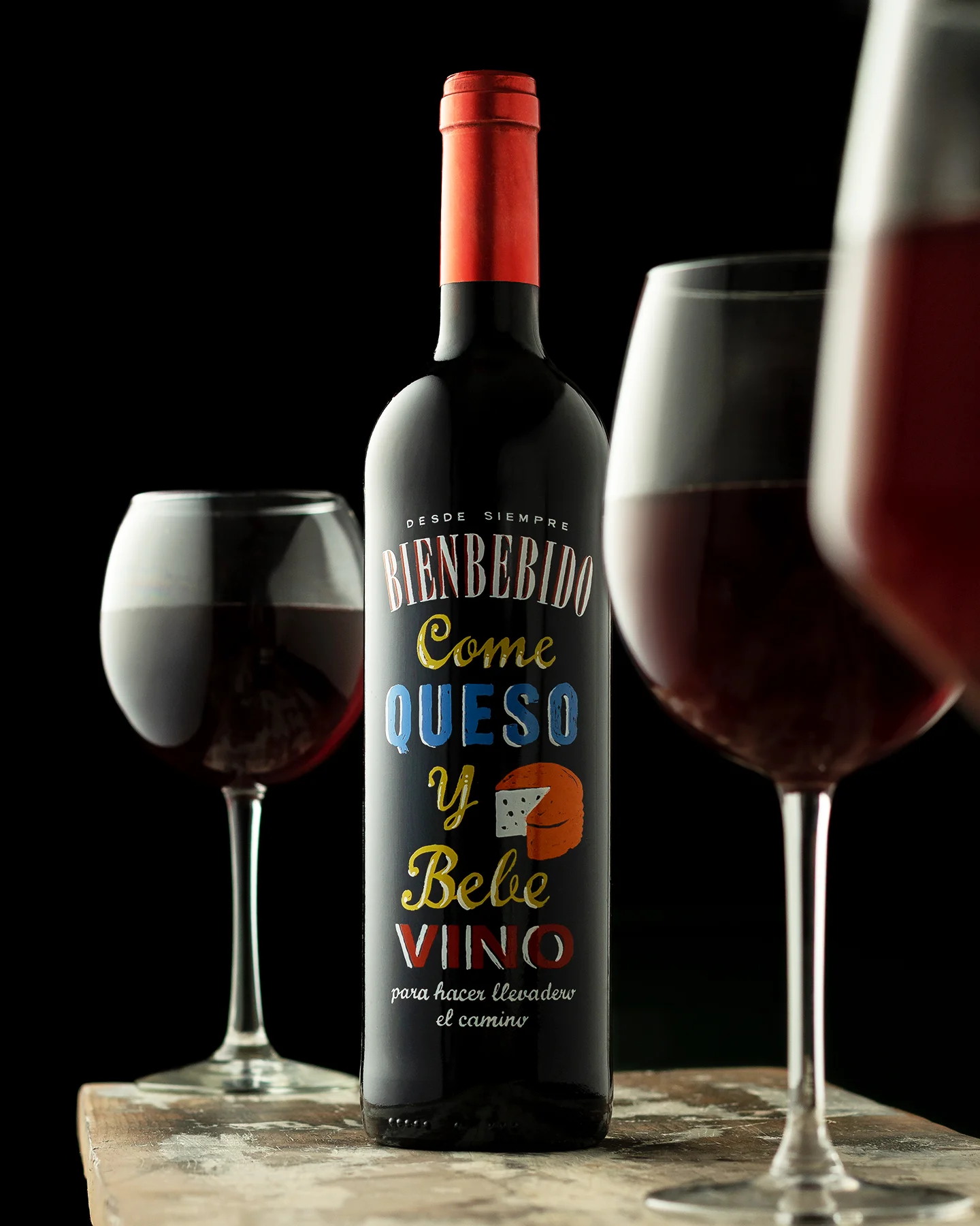 Fotografía publicitaria de vino tinto realizada en estudio, con control de iluminación, fondo negro y enfoque en etiqueta y presentación del producto.