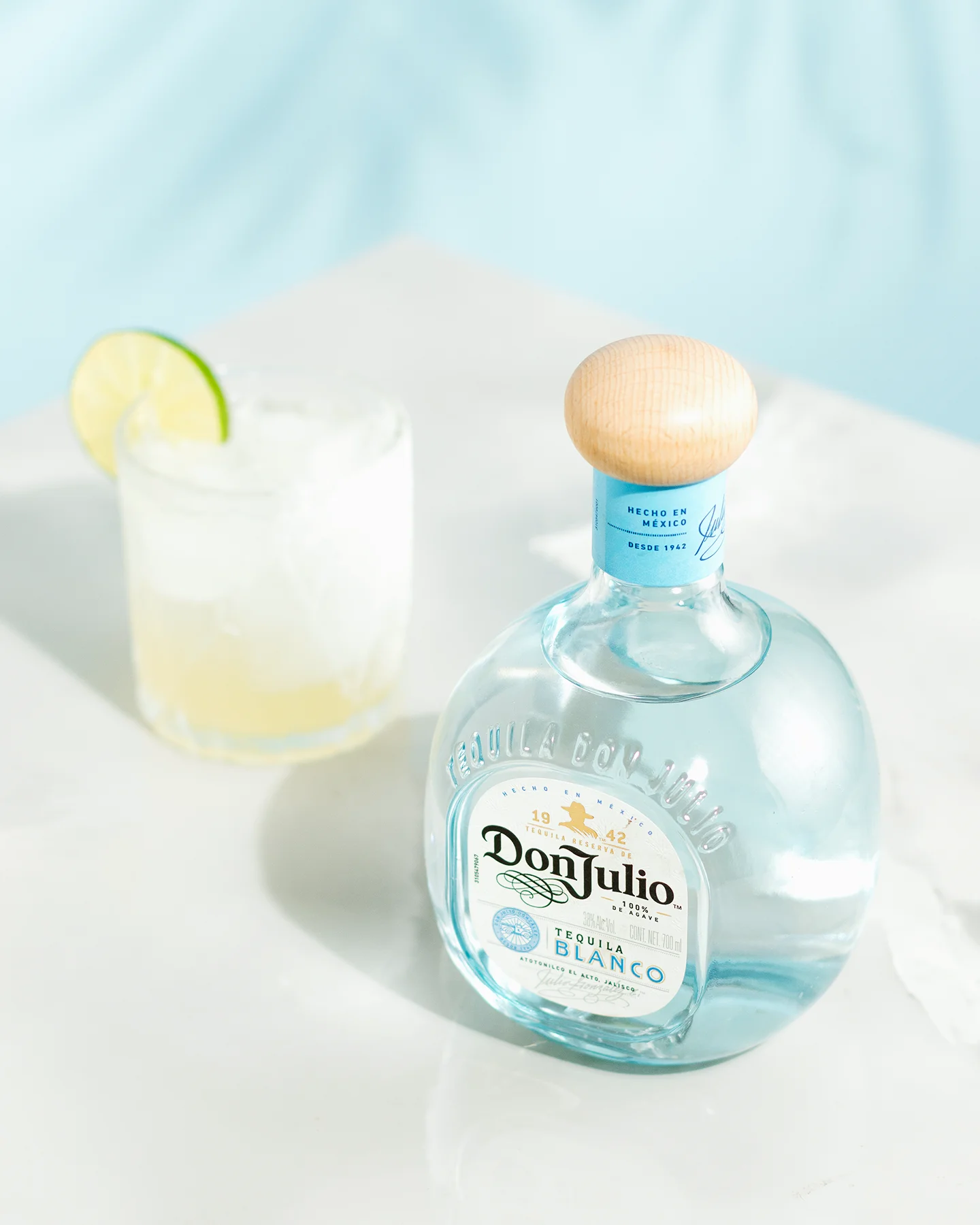Fotografía comercial estilo de vida: botella de Tequila Don Julio Blanco acompañada de vaso con cóctel de limón.