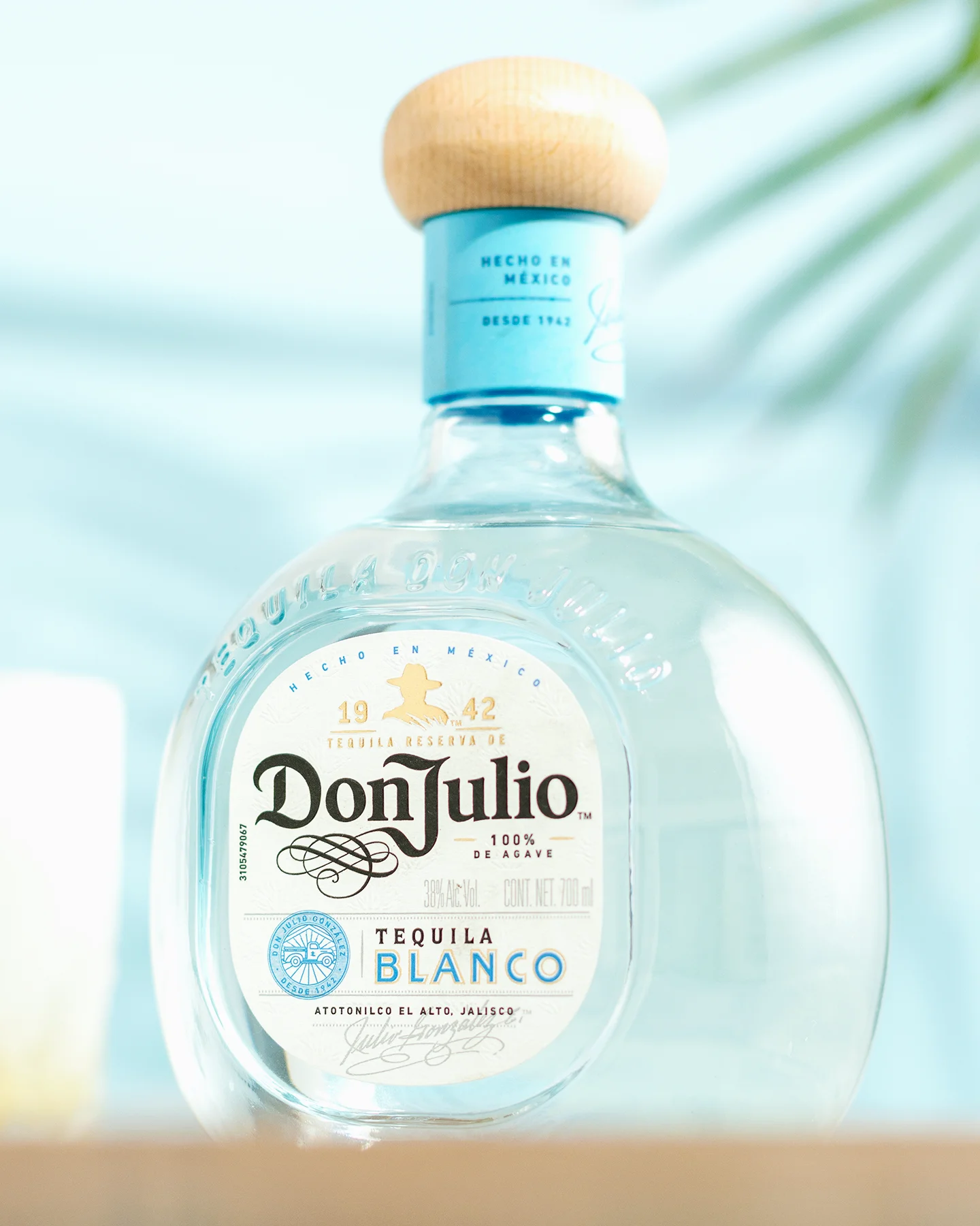 Fotografía publicitaria de licor: botella de Tequila Don Julio Blanco sobre barra con iluminación tropical en Chihuahua.